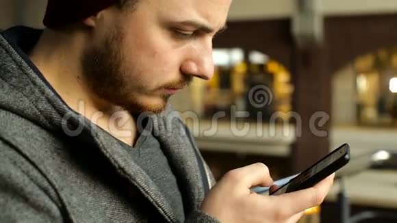 年轻快乐男人坐在咖啡馆里的智能手机画像视频的预览图