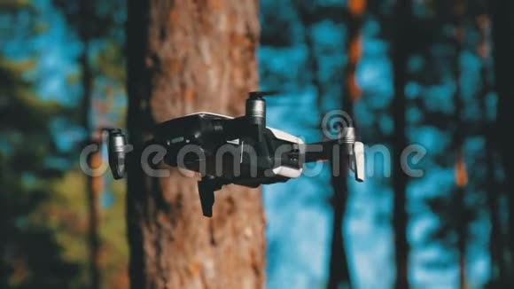 带着摄像机的无人机在空中盘旋四架直升机飞越森林的地面视频的预览图