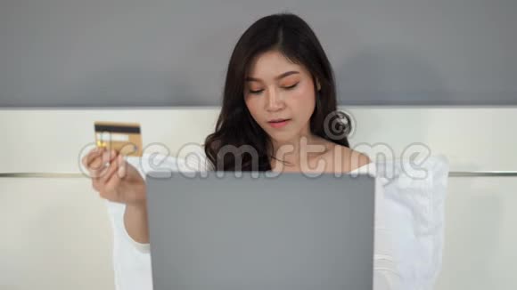 妇女在网上购物床上有信用卡和笔记本电脑视频的预览图