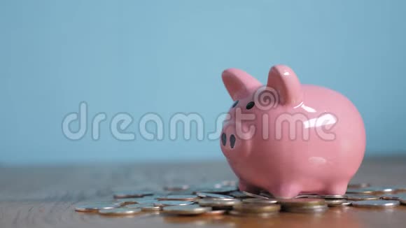 小猪银行业务站在一堆生活方式的硬币概念上一只手把硬币放在黄色的储蓄罐里视频的预览图