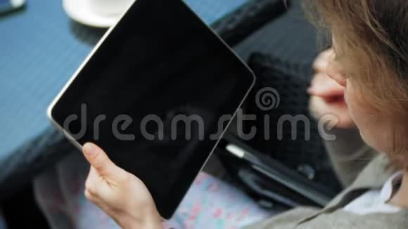 年轻女子在咖啡馆的酒吧里享受平板电脑视频的预览图