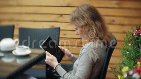年轻女子在咖啡馆的酒吧里享受平板电脑视频的预览图