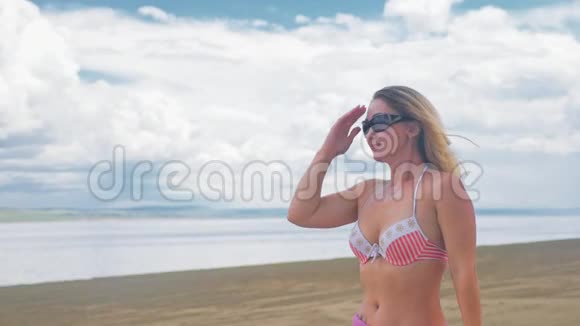 漂亮的女人戴着帽子站在海滩上靠在蓝色的大海上视频的预览图