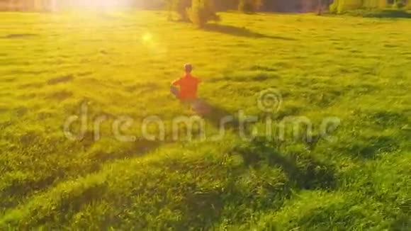 低空径向飞行超过运动瑜伽男子在完美的绿草在山上日落视频的预览图