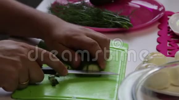一个人从盘子里拿出一根黄瓜然后开始在切割板上切割视频的预览图