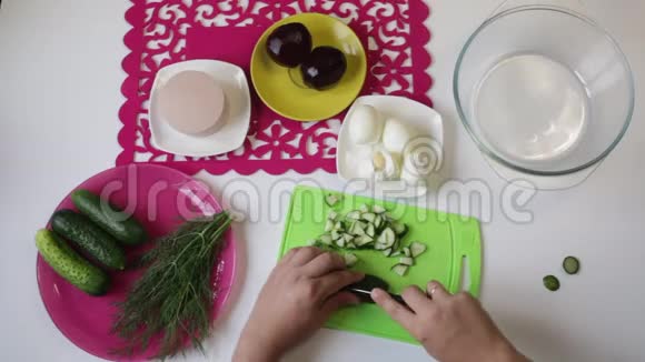 一个人从盘子里拿出一根黄瓜然后开始在切割板上切割视频的预览图