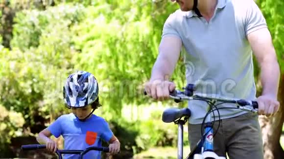 爸爸和小儿子一起在公园骑自行车视频的预览图