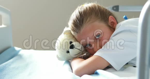 带着玩具熊躺在床上的生病女孩视频的预览图
