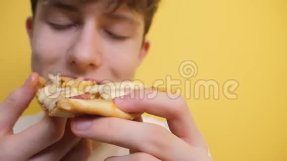 披萨快乐的青少年男孩吃一片披萨的概念小男孩饿了吃一片披萨生活方式慢动作视频的预览图