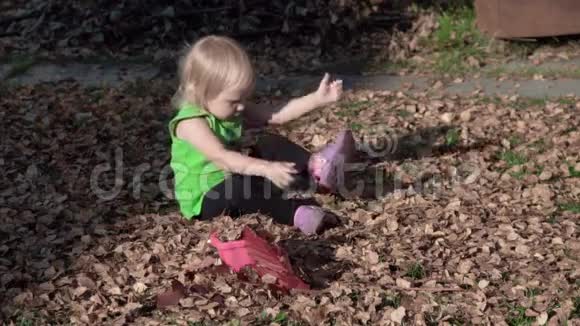可爱的女婴在秋天玩树叶视频的预览图