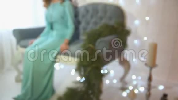 女人坐在一张豪华沙发上靠近白色砖墙装饰着花环视频的预览图