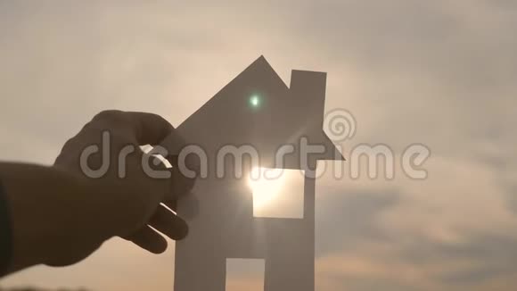 幸福家园建设理念一个男人手里拿着一个纸房子他的生活方式手里拿着夕阳剪影视频的预览图
