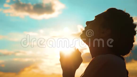 女孩在祈祷女孩在日落时交叉双手祈祷剪影慢生活方式运动视频女孩双手合拢视频的预览图