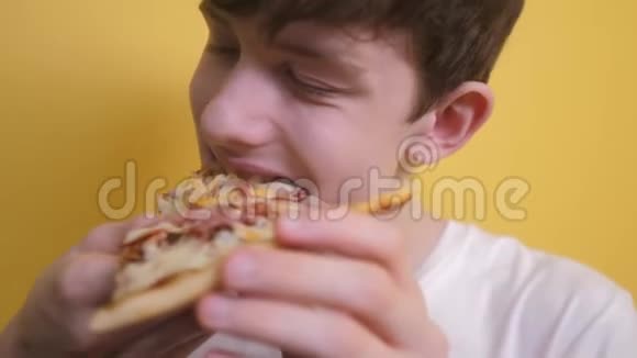 披萨快乐的青少年男孩吃一片披萨的概念十几岁的男孩饿了吃一片披萨慢速视频视频的预览图