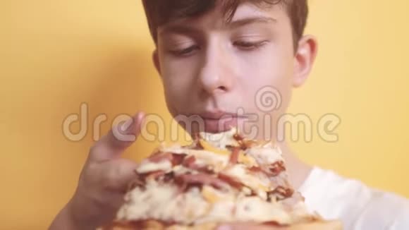 快乐的小男孩吃一片披萨的概念少年男孩饿了吃一片比萨饼的生活方式慢速视频视频的预览图