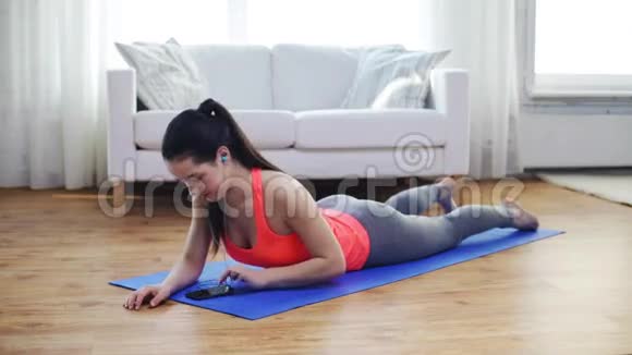 带着智能手机在家锻炼的微笑女人视频的预览图