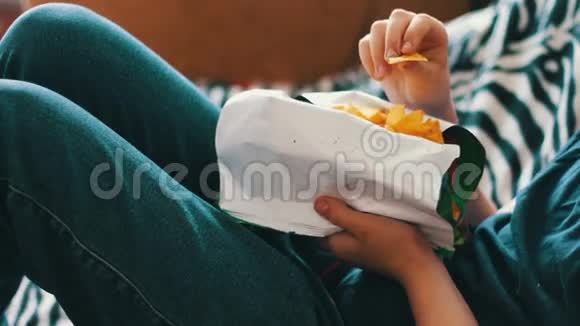 男孩十几岁的孩子在家里用手在沙发上吃薯片视频的预览图