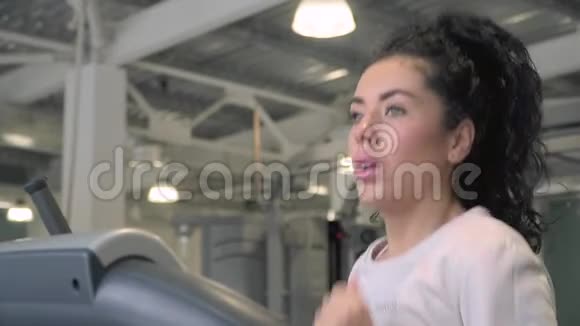 年轻女子在健身房跑步机上跑步视频的预览图
