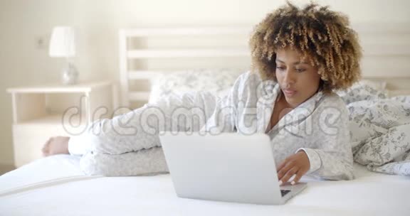 可爱的女人在床上用笔记本电脑视频的预览图