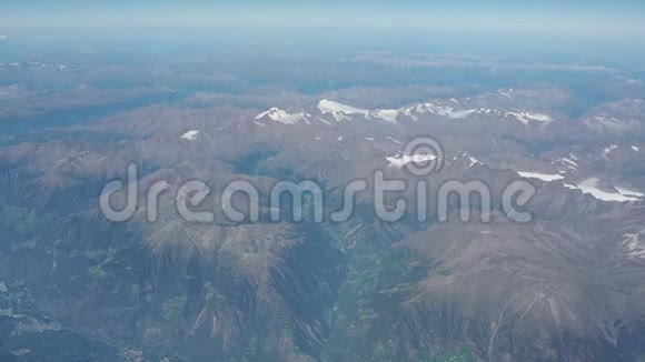 在夏季飞越阿尔卑斯山冰川的景观从飞机窗口可以看到空中景色视频的预览图