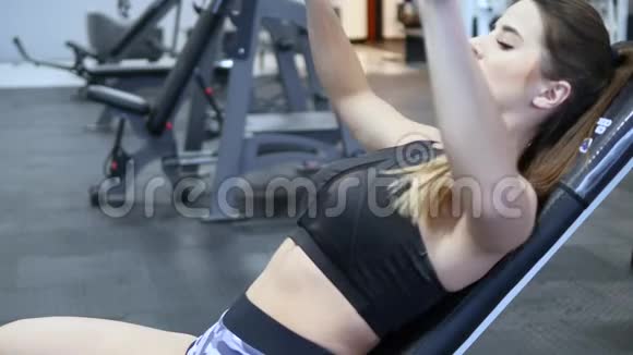 女子在健身房的模拟器上训练手臂和肩膀视频的预览图