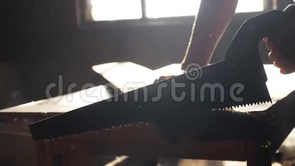 人木匠手工制作和工艺概念慢动作视频木工在车间里锯树从一个车间里锯阳光视频的预览图