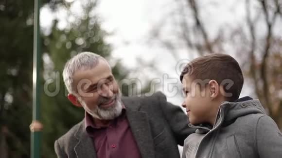 爷爷和孙子一起在公园里度过时光他们坐在长凳上视频的预览图