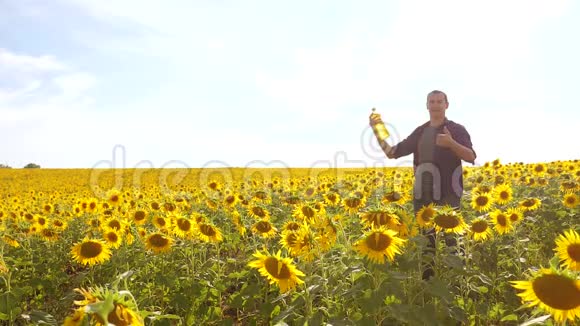 农夫手捧一瓶葵花籽油夕阳西下的田野生活方式人类关于葵花籽油生产的节目视频的预览图