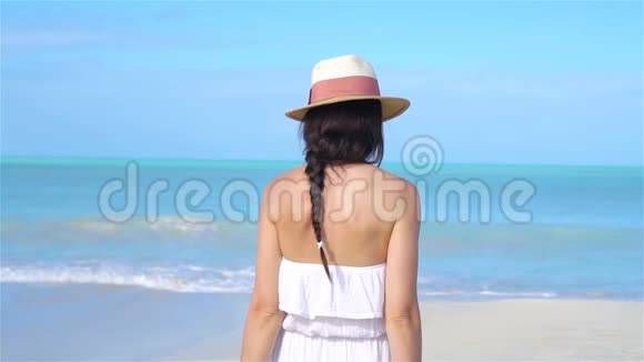 在白色海滩散步的年轻快乐女人视频的预览图