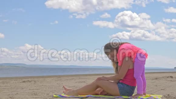 小可爱的女孩和海滩上的年轻母亲视频的预览图