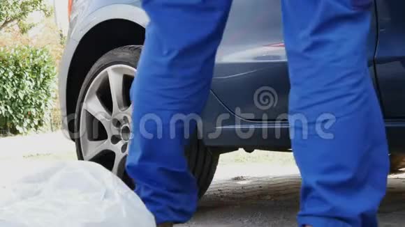 一个穿工作裤的人取代了汽车车轮视频的预览图