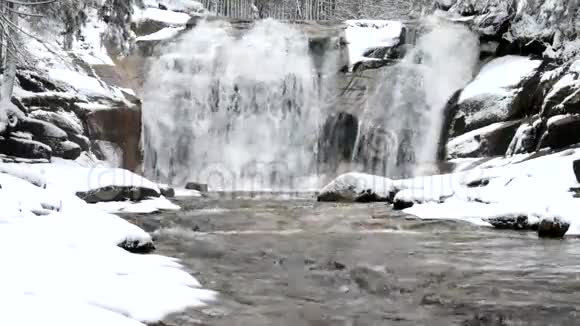 冬季瀑布小池塘和白雪皑皑的巨石瀑布层层叠叠山河的水晶冻水和声音视频的预览图