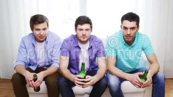 快乐的男性朋友在家看啤酒电视视频的预览图