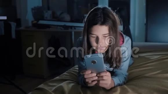 十几岁的女孩网上购物在床上看智能手机少女风帽生活方式写的视频的预览图