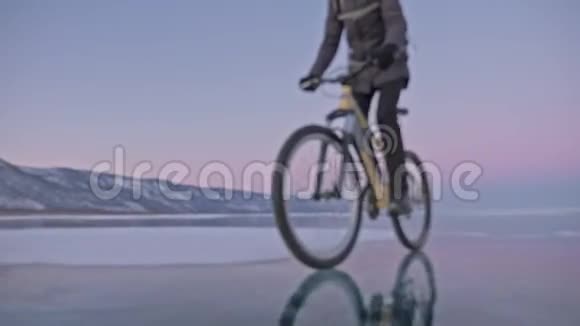 人在冰上骑自行车骑自行车的人穿着灰色的羽绒服背包和头盔冰冻的冰视频的预览图