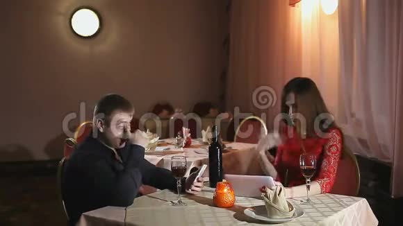 男人和女孩带着智能手机和平板电脑在咖啡馆浪漫的夜晚视频的预览图