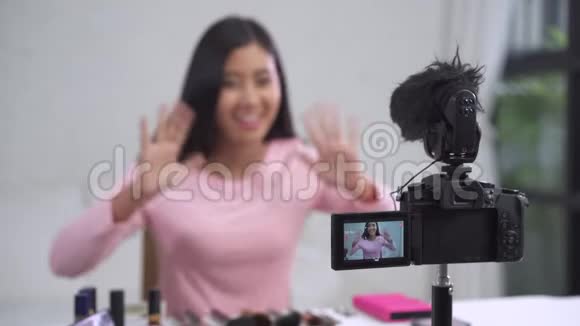 美女博主一边呈现美容化妆品一边坐在镜头前录制视频视频的预览图