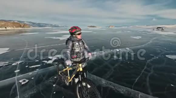 女人在冰上骑着自行车走着女孩穿着银色的羽绒服背包和头盔冰冰视频的预览图