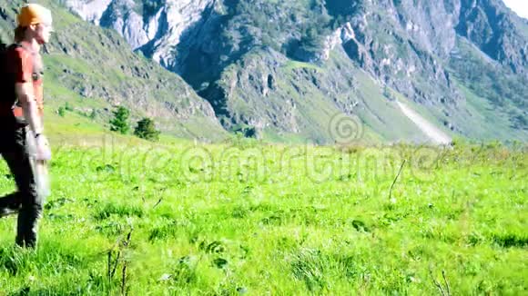 徒步旅行者带着背包在绿色的山地草地上行走夏季运动和娱乐理念视频的预览图