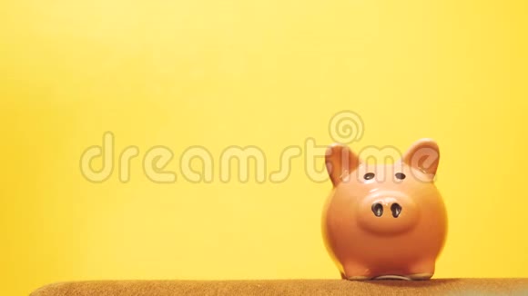 猪的生活方式银行的商业理念一只手把硬币放在黄色背景上的储蓄罐里省钱就是视频的预览图