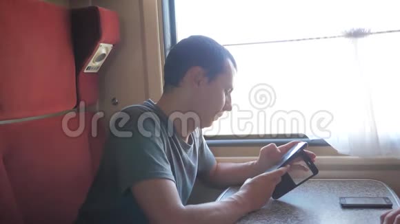 休闲男子从手机屏幕阅读同时阅读短信旅行的火车旅行车慢速视频视频的预览图