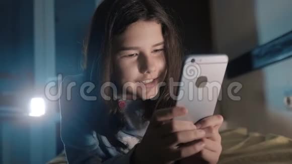 十几岁的女孩在网上生活方式购物时她的智能手机在床上过夜一个小少女写的视频的预览图