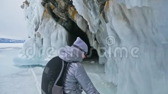 贝加尔湖冰上女子旅行去冬岛旅行女孩走在冰岩脚下旅行者看着视频的预览图