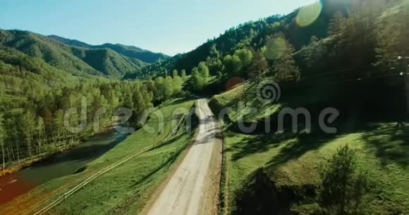 空中UHD4K视野在阳光充足的山地乡村土路和草地上低空飞行视频的预览图