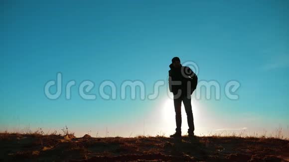 一个值得去旅游的男人带着狗背包站在山顶上日落时的人剪影徒步旅行者冒险视频的预览图