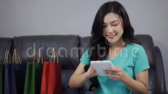 幸福的女人用数码平板电脑在客厅网购视频的预览图