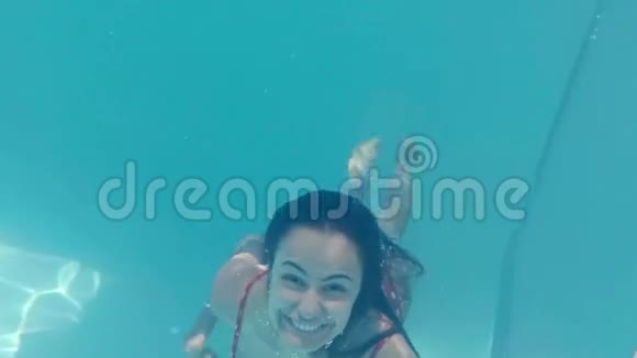美丽的女人在水下游泳对着镜头微笑视频的预览图
