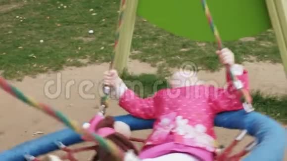 一个穿着粉红色裙子的小女孩在操场上荡秋千视频的预览图