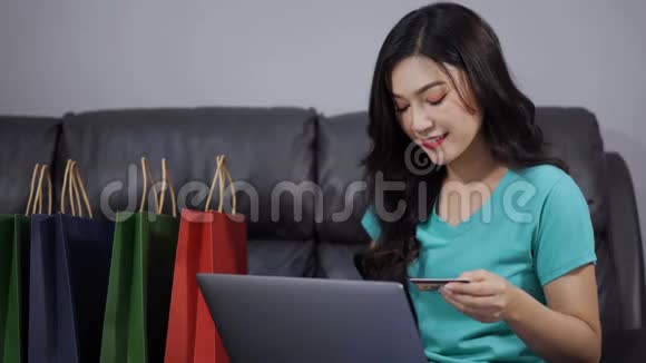 幸福的女人用笔记本电脑上网购物客厅里有信用卡视频的预览图