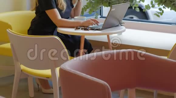 商务女性坐在咖啡馆的桌子旁喝咖啡在笔记本电脑上工作视频的预览图